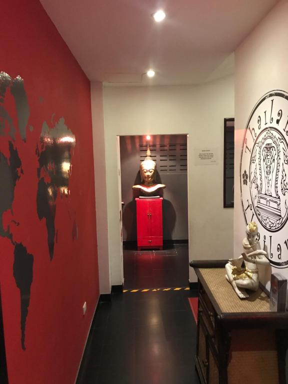 um corredor com uma estátua num quarto com uma parede vermelha em Lotus Art Guesthouse em Pattaya Sul