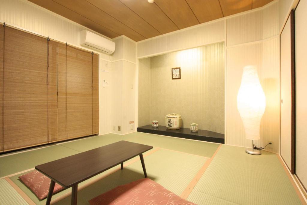 Toyotaya Hostel في نيشينومايا: غرفة معيشة مع طاولة ومصباح