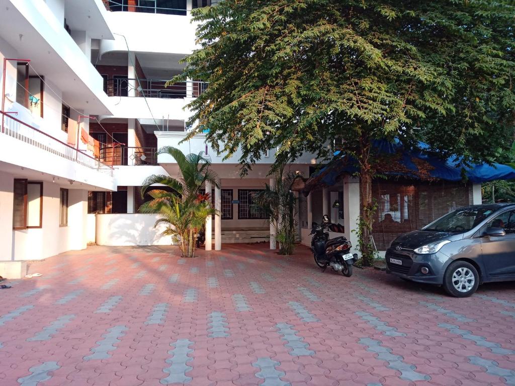 un'auto e una moto parcheggiate di fronte a un edificio di Hotel Peacock a Kovalam