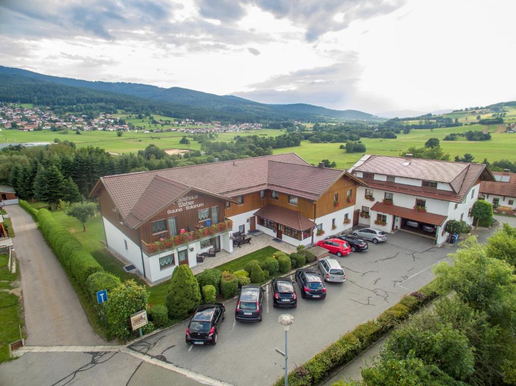 ein großes Haus mit Autos auf einem Parkplatz in der Unterkunft Gästehaus Weber in Arrach