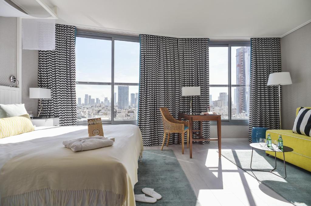 um quarto com uma cama grande, uma secretária e janelas em Melody Hotel - an Atlas Boutique Hotel em Tel Aviv