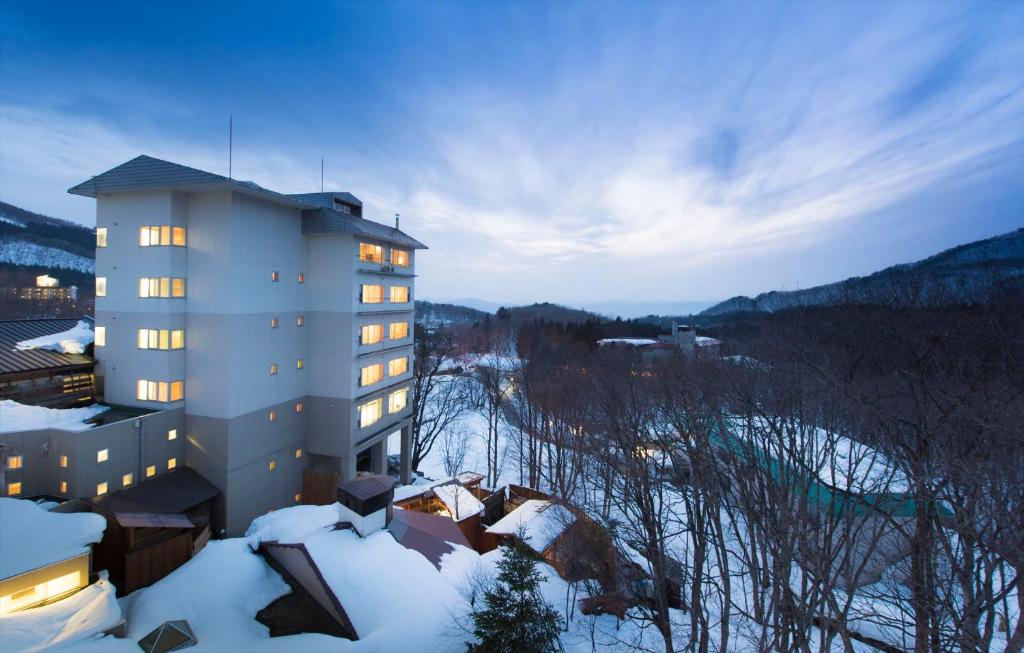 a building with lights on in the snow at Takamiya Hotel Lucent in Zao Onsen