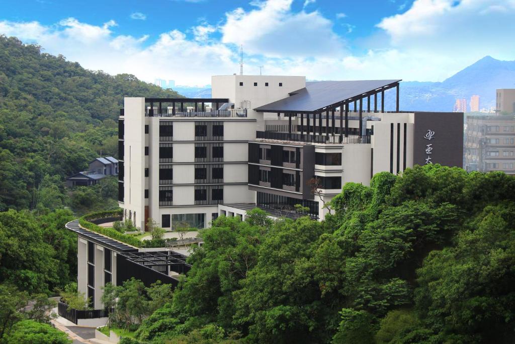 台北市にあるアジア パシフィック ホテル ベイトウの木立の丘の上の白い大きな建物