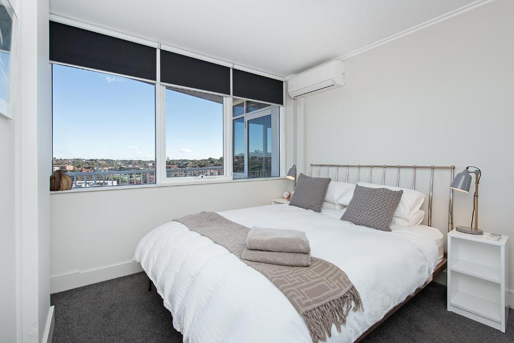 a bedroom with a large white bed and large windows at Stunning Ocean View Apartment !!! in Sydney