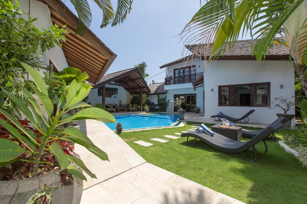 un patio trasero con piscina y una casa en Villa Origami by Nagisa Bali, en Seminyak
