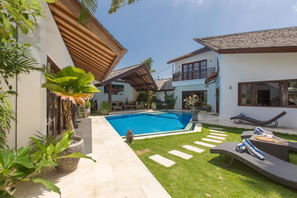 a backyard with a swimming pool and a house at Villa Origami by Nagisa Bali in Seminyak