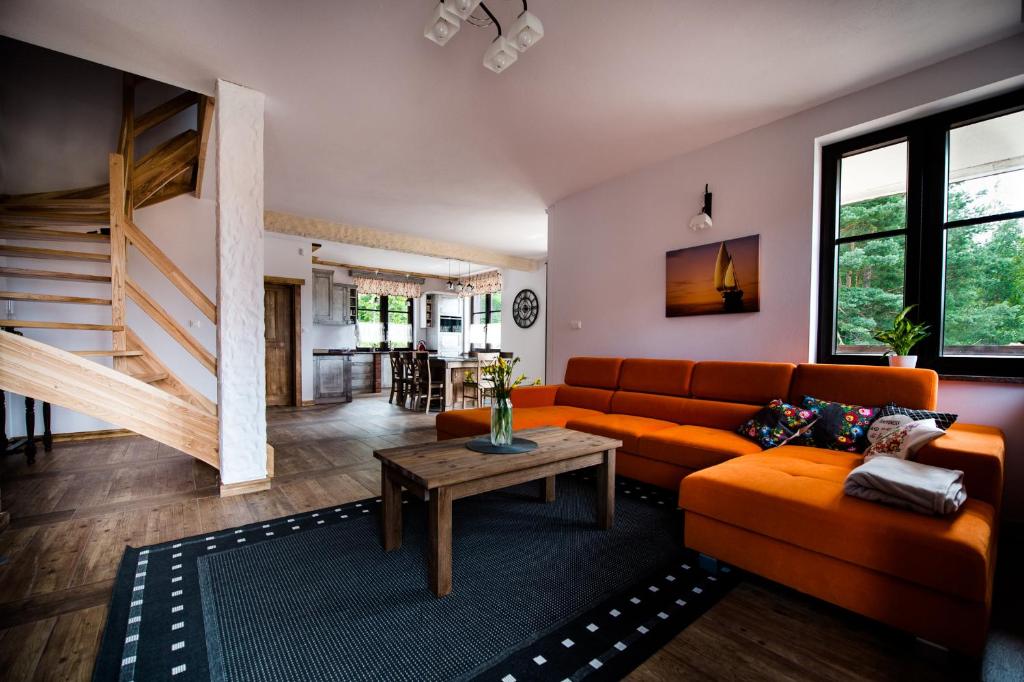 a living room with an orange couch and a table at DWÓR U PAPUGA in Ruciane-Nida