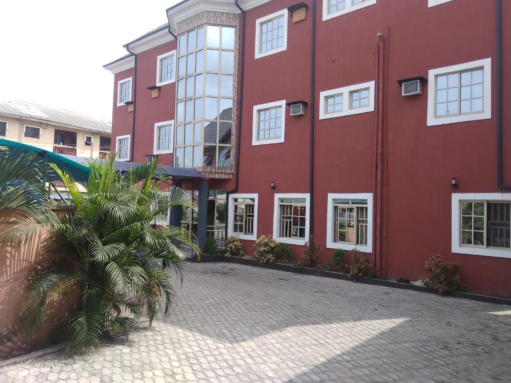 a red building with a palm tree in front of it at Lakewood Hotels in Port Harcourt