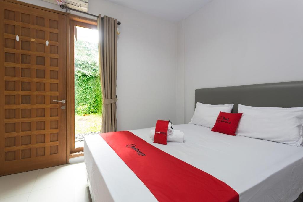 una camera da letto con un letto con cuscini rossi e una porta di RedDoorz Plus near Cilandak Town Square 2 a Giacarta
