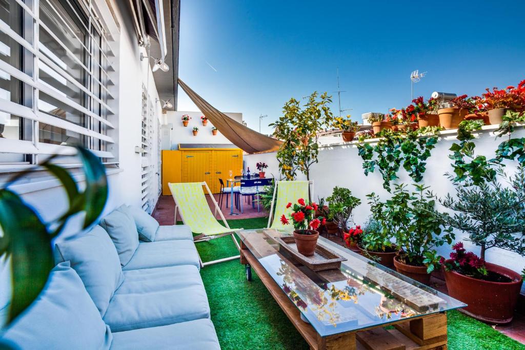 un patio con sillas, mesa y plantas en Encantador Ático con Terraza, en Sevilla