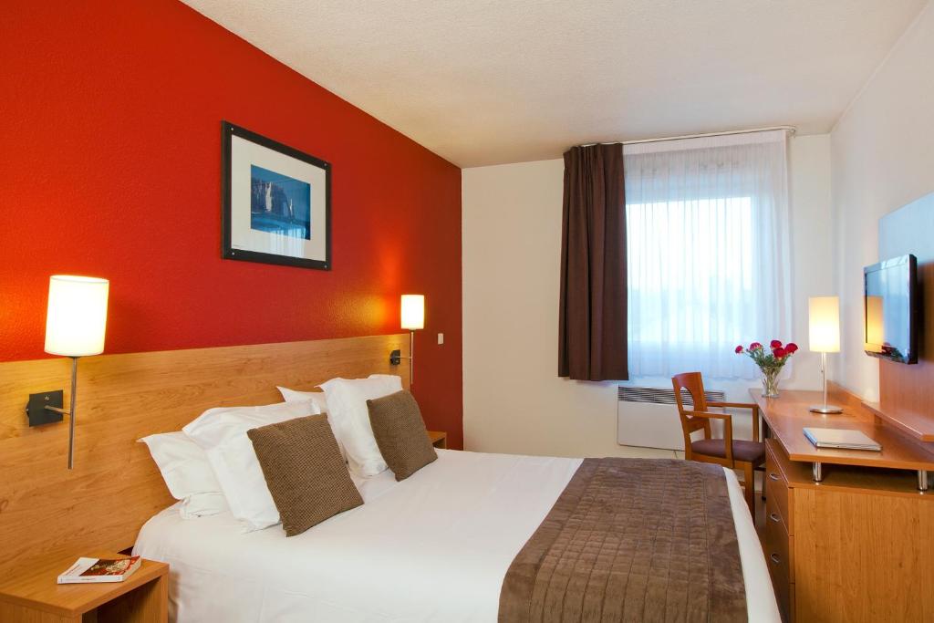 ルーアンにあるSéjours & Affaires Rouen Normandieの大きなベッドとデスクが備わるホテルルームです。