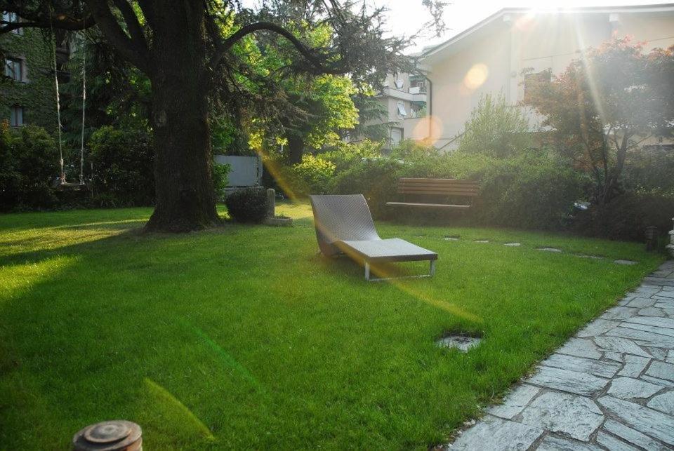 蒙扎的住宿－La Villa Del Cedro，坐在树旁的草地上的公园长凳