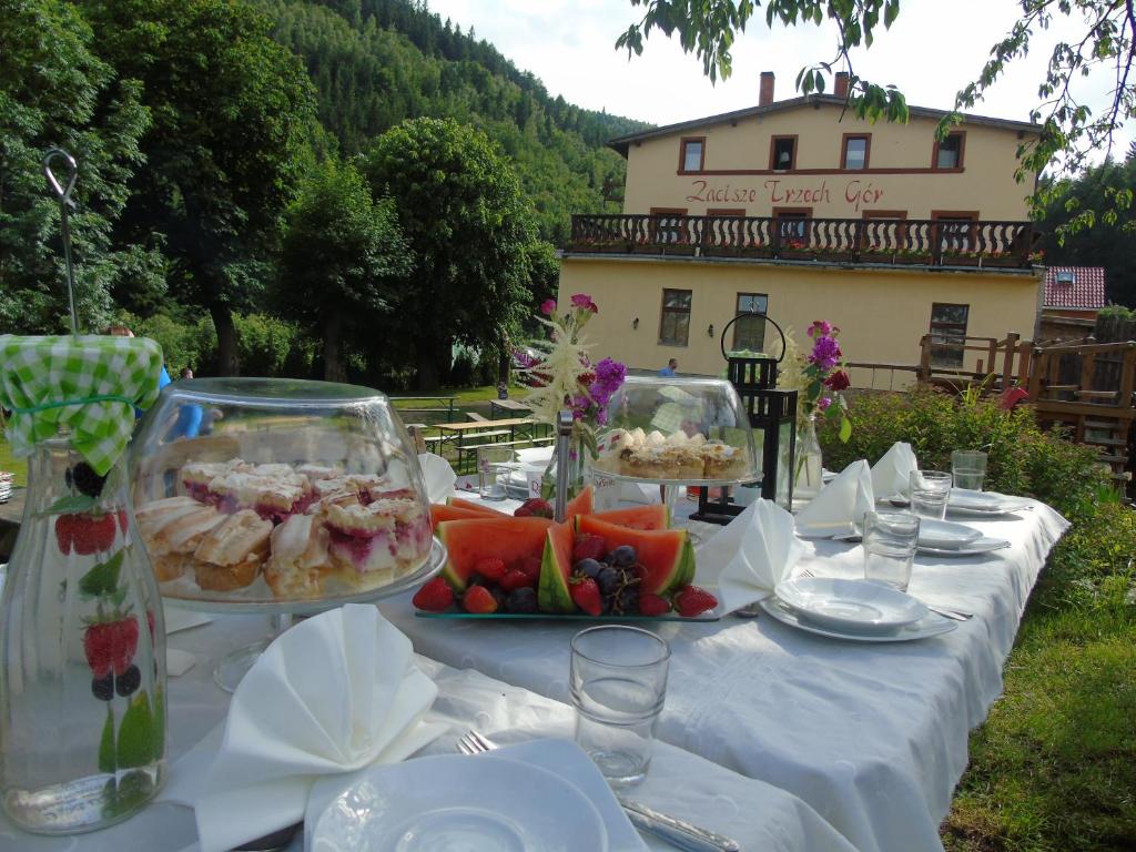 a table with a white table cloth with food on it at Zacisze Trzech Gór in Jedlina-Zdrój