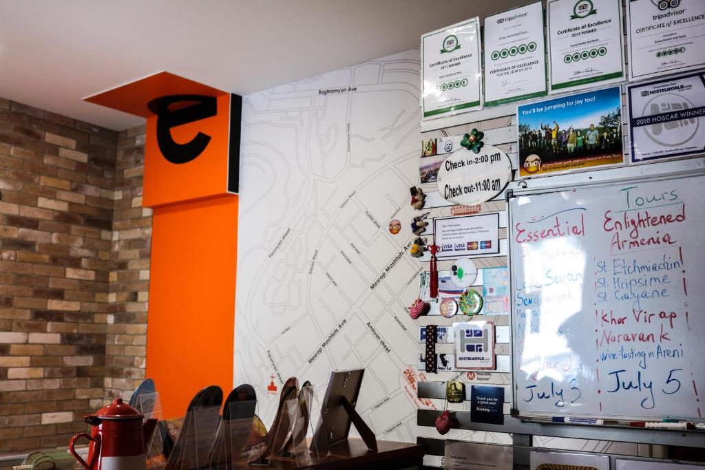 una habitación con una pared con carteles y zapatos. en Envoy Hostel & Tours, en Ereván