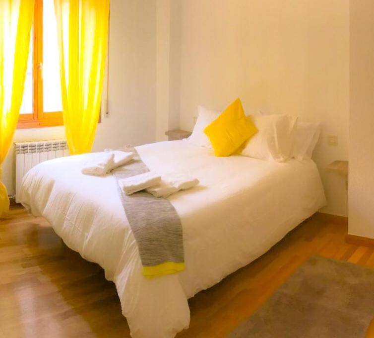a bedroom with a white bed with yellow curtains at AZ El Balcón de Conde de Aranda II in Zaragoza