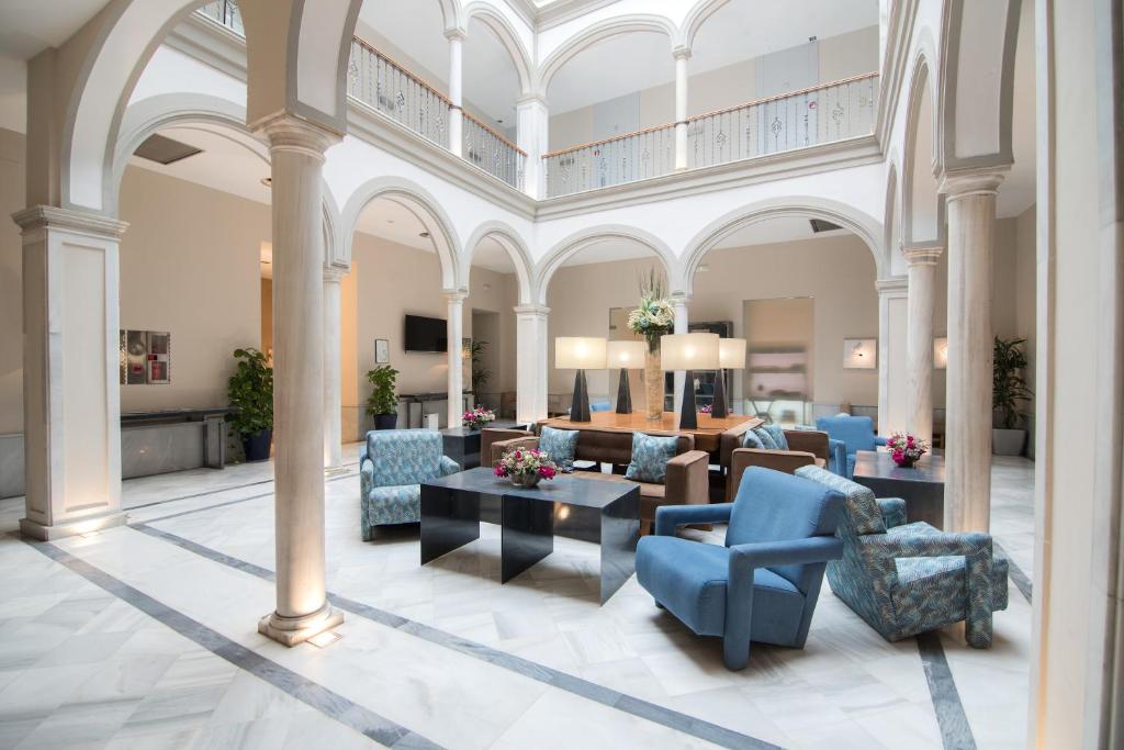 uma grande sala de estar com cadeiras e mesas azuis em Petit Palace Marques Santa Ana em Sevilha