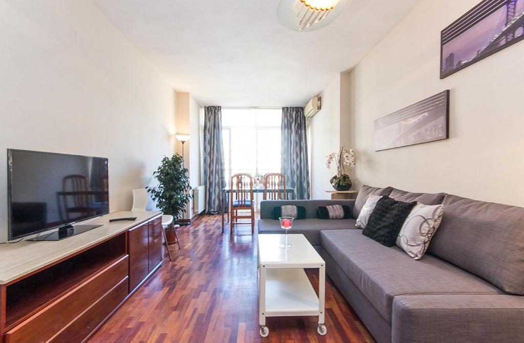 uma sala de estar com um sofá e uma televisão de ecrã plano em YOUR HOME - Central Apartment em Barcelona