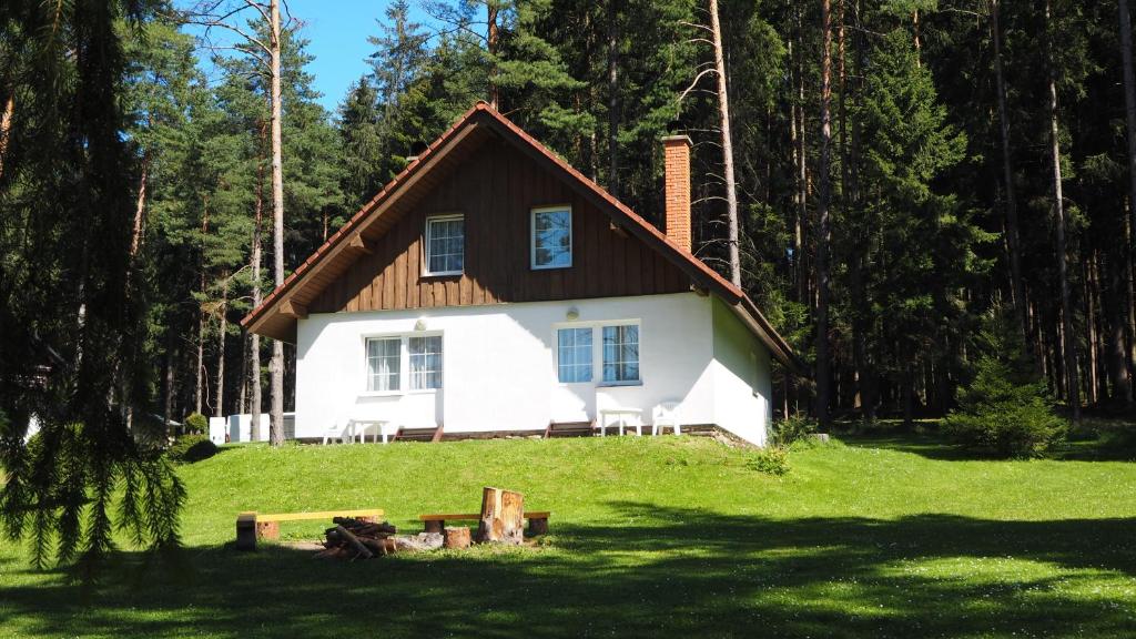 a white house with a brown roof in the grass at Lojzovy Paseky in Frymburk
