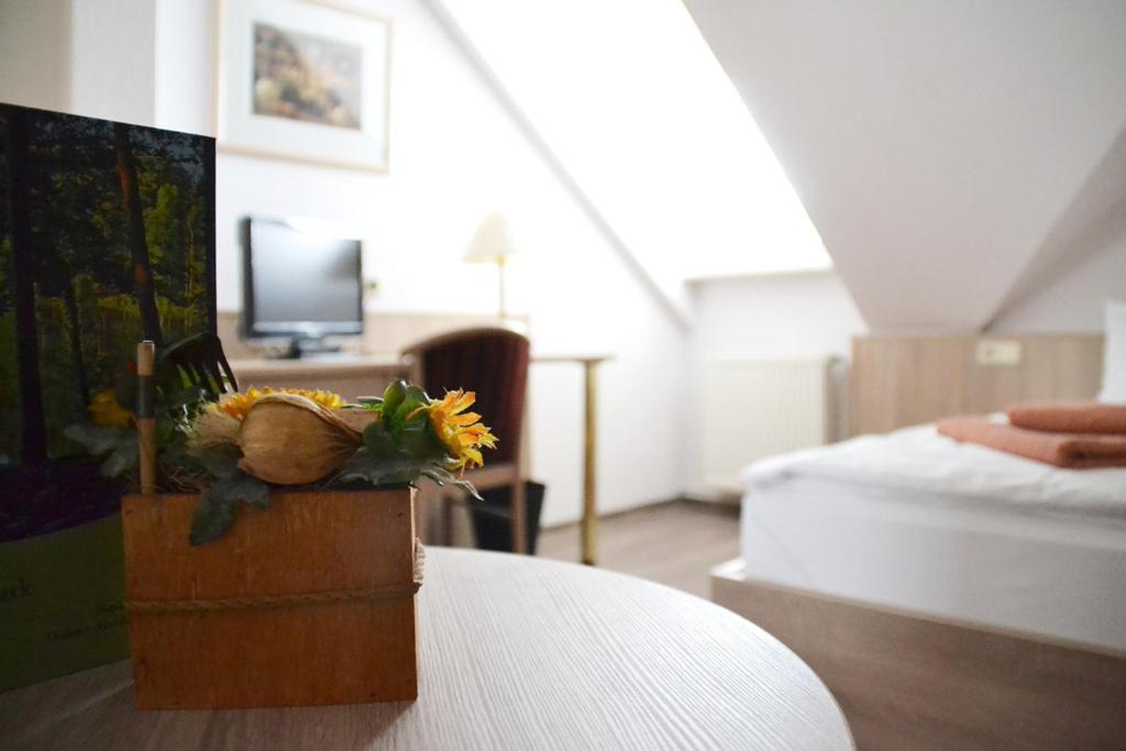シュトルコウにあるRestaurant & Pension Storchenklauseのベッド1台、花瓶付きのテーブルが備わる客室です。