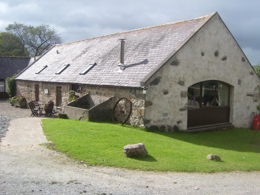 a stone barn with a clock on the roof at Parkmore Holiday Cottages in Dufftown