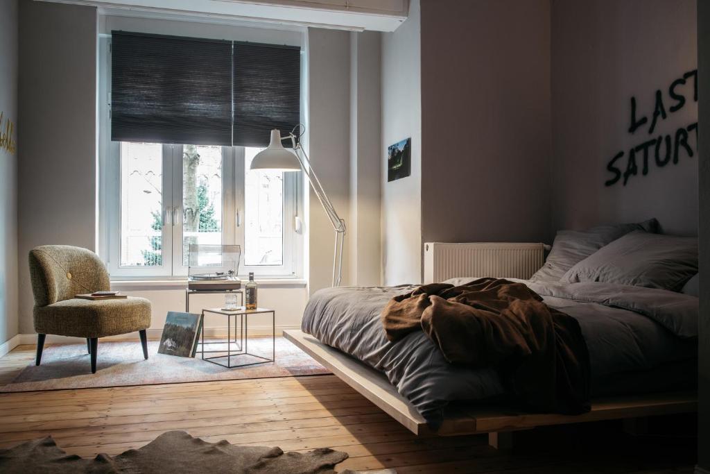 um quarto com uma cama, uma cadeira e uma janela em Urbn Dreams em Berlim