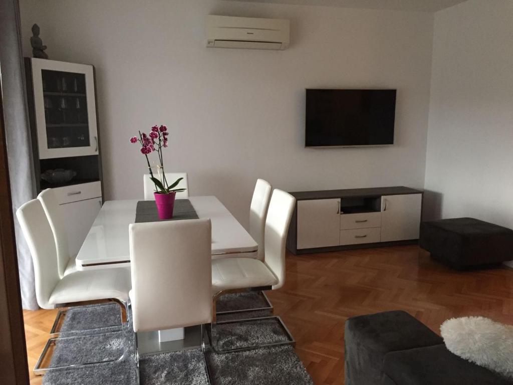 uma sala de estar com uma mesa e cadeiras e uma televisão em Villa Silvija em Mlini