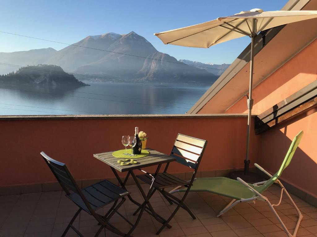 a table with two chairs and an umbrella on a balcony at New Attic Lake View 4 in Varenna