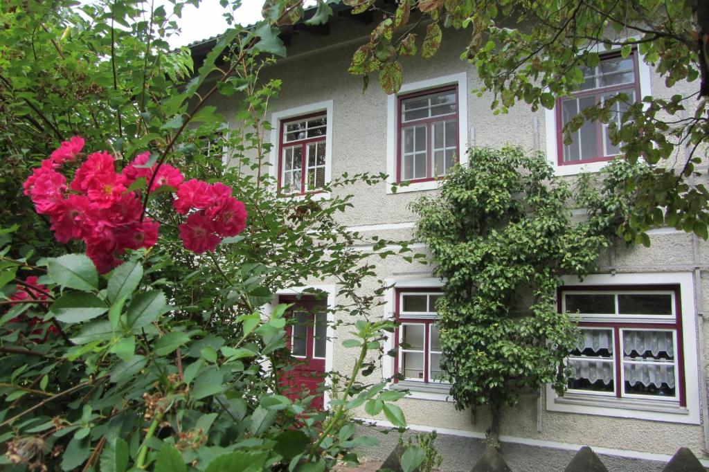 une maison avec des fleurs rouges devant elle dans l'établissement Alte Wirtschaft, à Hohenlinden