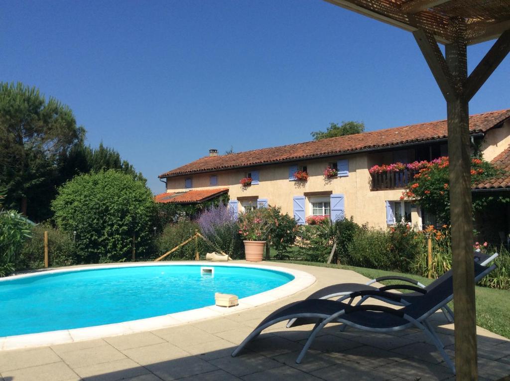 a villa with a swimming pool in front of a house at Chambres d'Hôtes L'Ardiegeoise in Ardiège