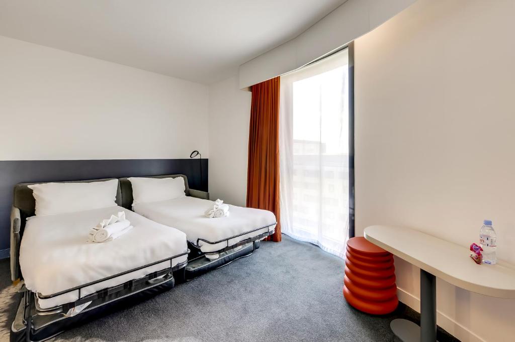 two beds in a room with a window at ibis Styles Paris Charles de Gaulle Airport in Roissy-en-France