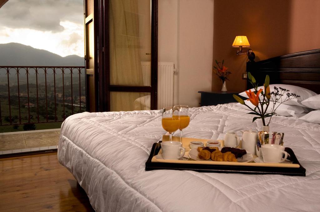 taca z napojami i pączkami na łóżku z balkonem w obiekcie Vytina Mountain View Hotel w mieście Vytina