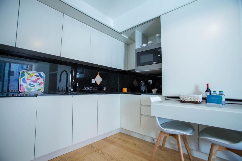 a white kitchen with white cabinets and a counter at Almada Story Apartments by Porto City Hosts in Porto