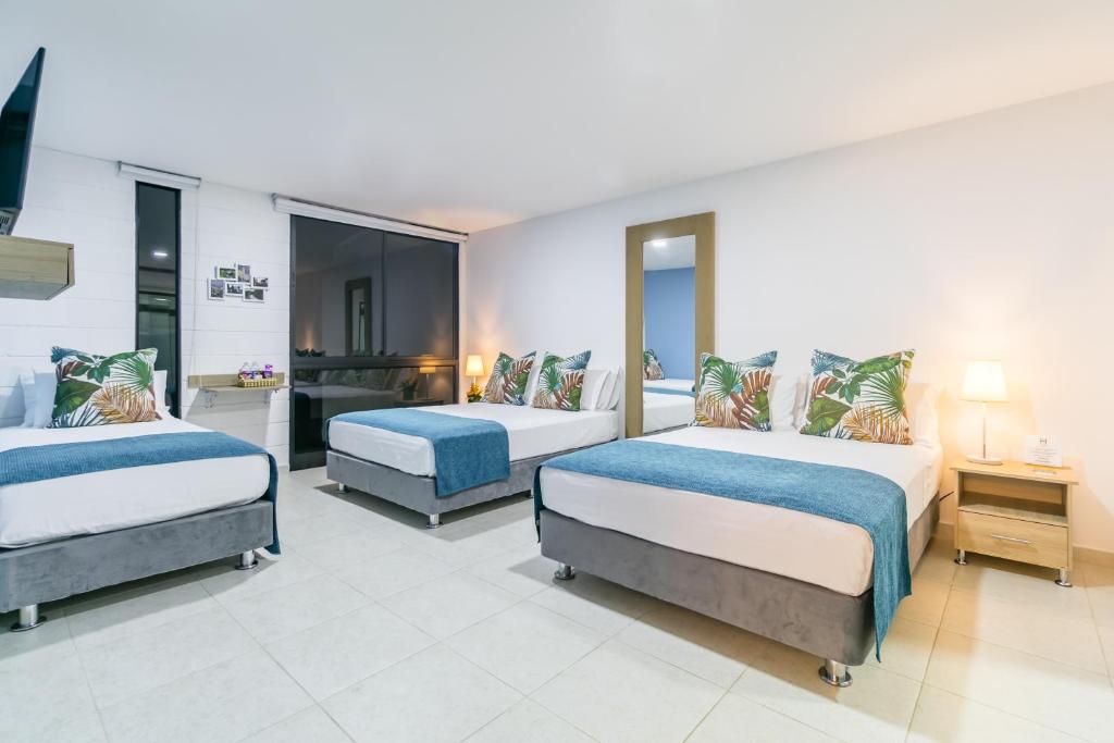 a bedroom with three beds and a desk in it at Hotel Casa Vallecaucana in Cali