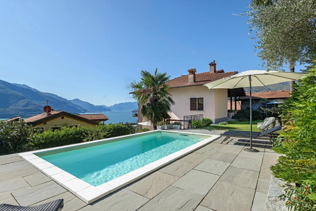 a swimming pool with an umbrella next to a house at Casa Artis in Gravedona