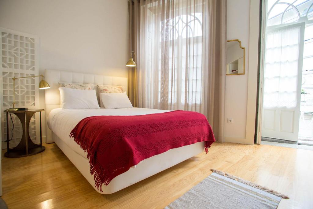 a bedroom with a large bed with a red blanket at Almada Story Apartments by Porto City Hosts in Porto