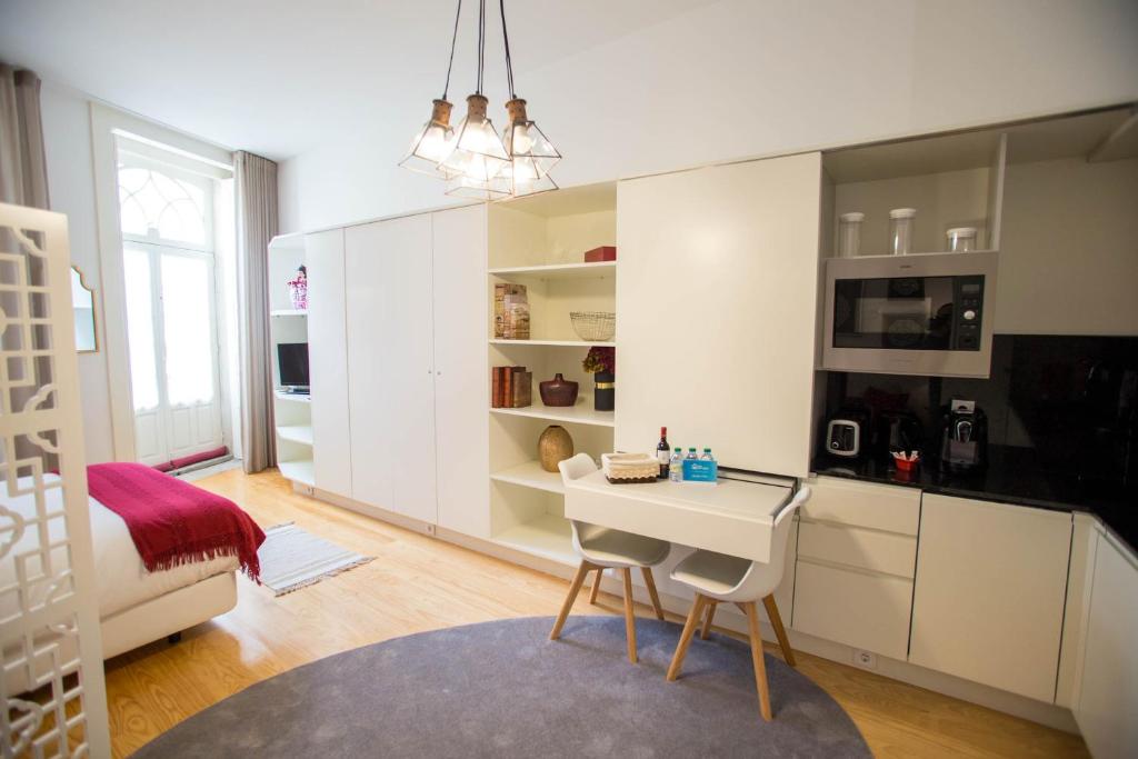 a kitchen with white cabinets and a table and chairs at Almada Story Apartments by Porto City Hosts in Porto