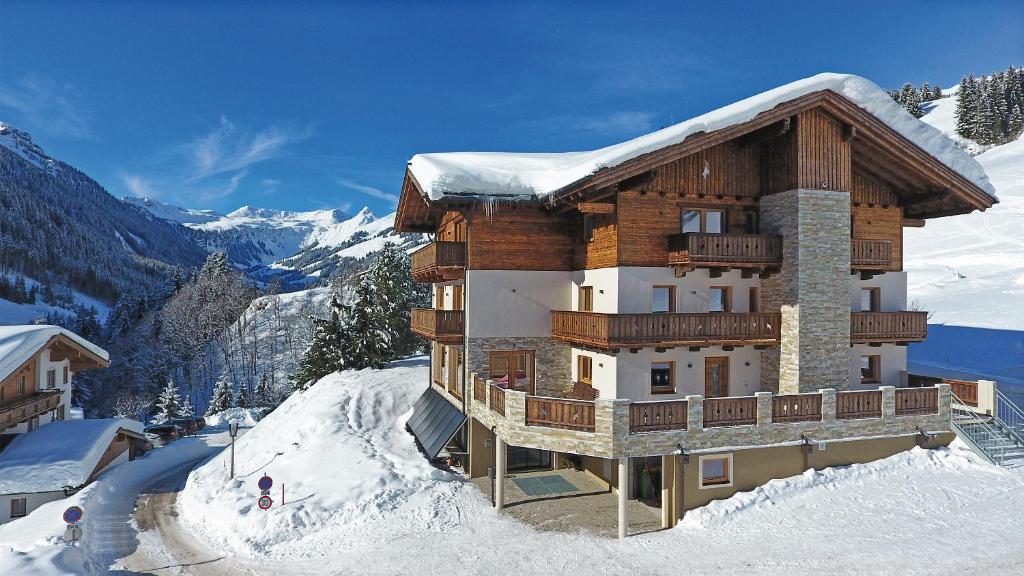 a building on top of a snow covered mountain at Appartement Berghof in Saalbach-Hinterglemm