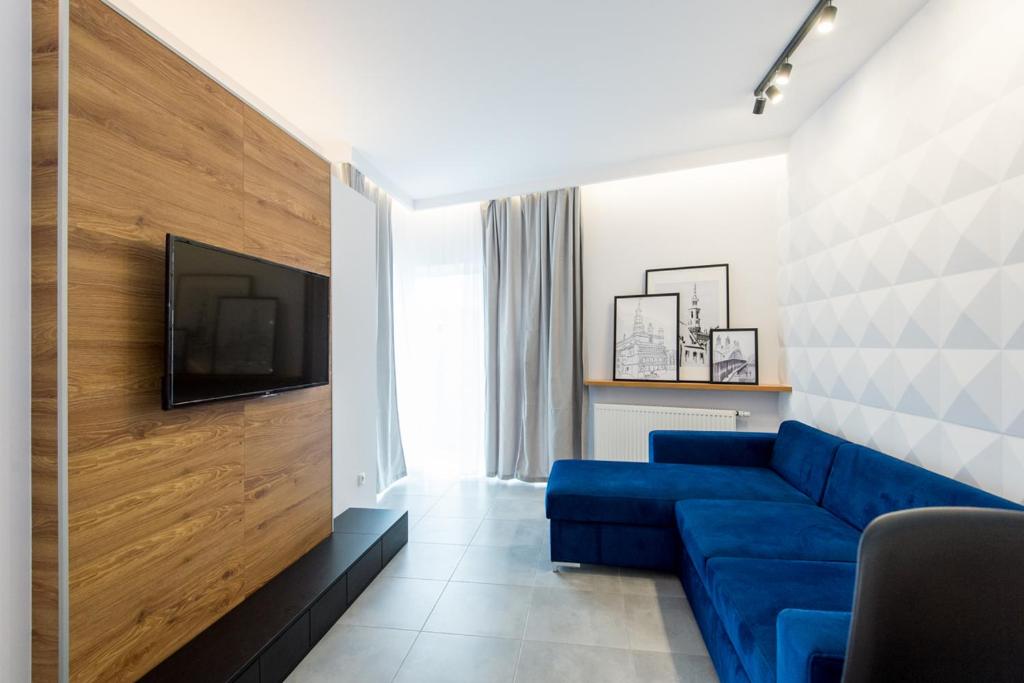 Una sala de estar con un sofá azul y un televisor. en Super-Apartamenty Luxury, en Poznan