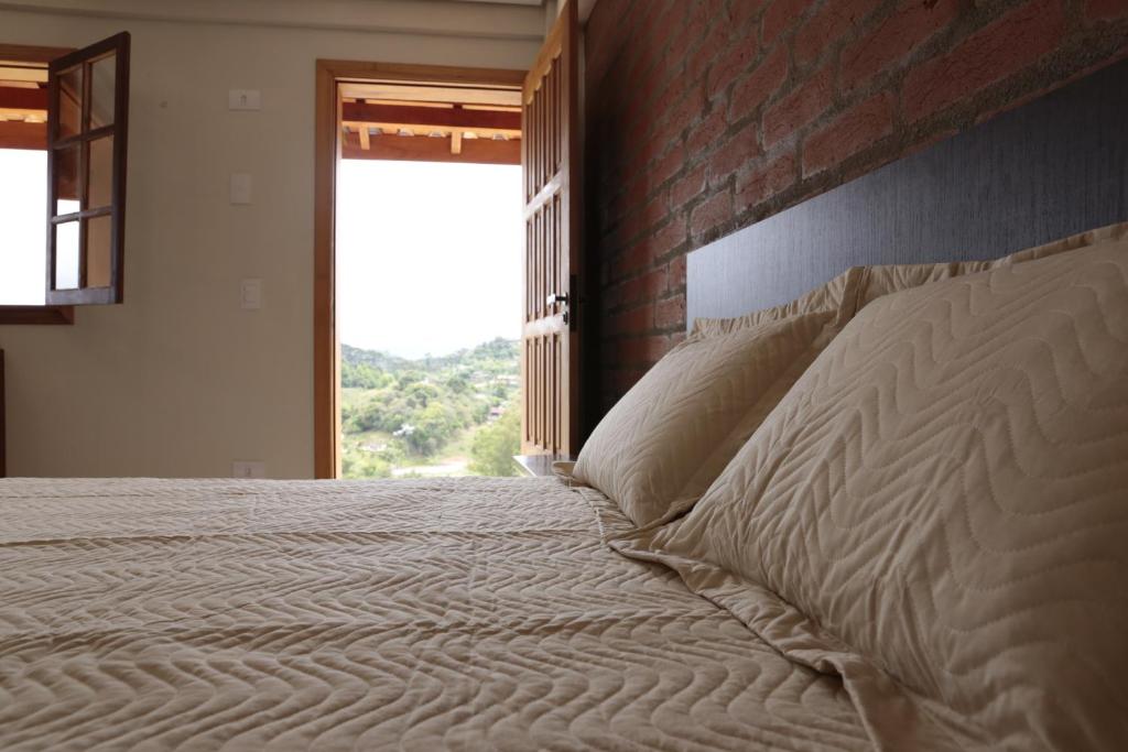 een slaapkamer met een bed met een bakstenen muur bij Repouso Mantiqueira in Santo Antônio do Pinhal