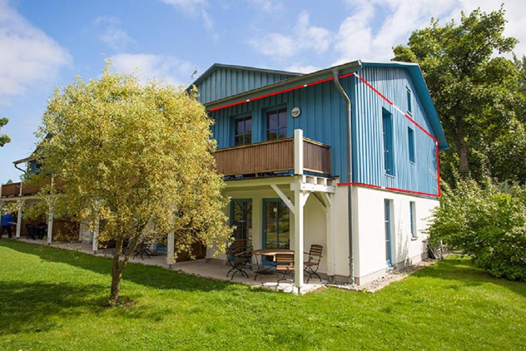 a blue and white house with a tree in the yard at Ferienwohnung Rügen-Freiheit in Putgarten