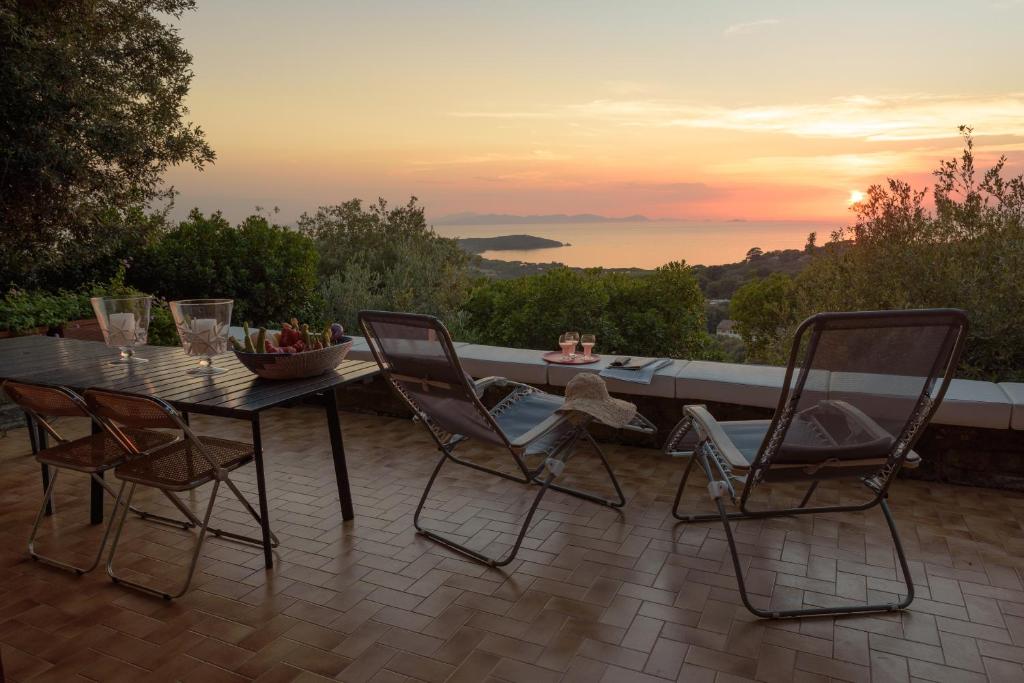 einen Tisch und Stühle auf einer Terrasse mit Blick auf den Sonnenuntergang in der Unterkunft Punta Ala Luxury Villa in Punta Ala