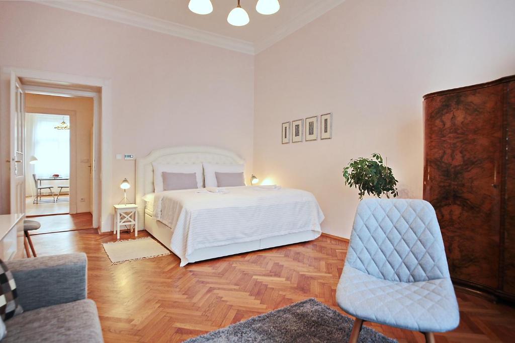 1 dormitorio blanco con 1 cama y 2 sillas en Apartment in the heart of Prague en Praga