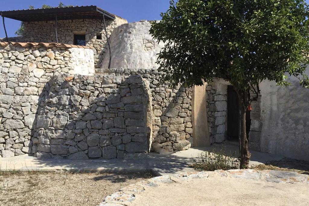 a stone building with a tree in front of it at Feudo Frammasi Bracchio in Salve
