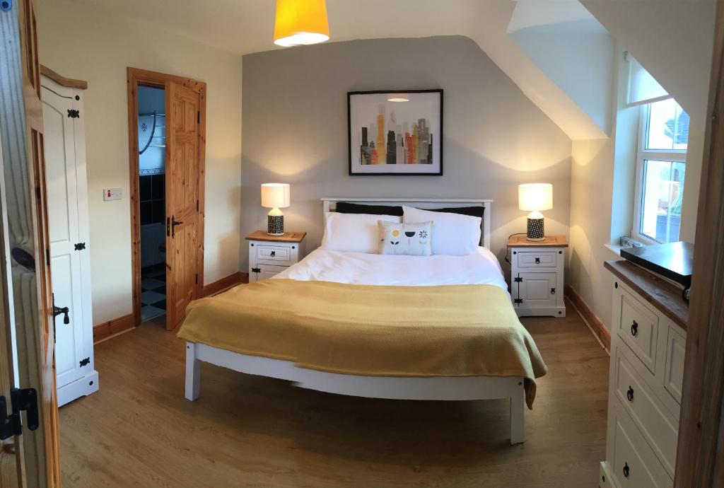 a bedroom with a large bed with two night stands and two lamps at No 4 Ballymastoker Cottage in Portsalon