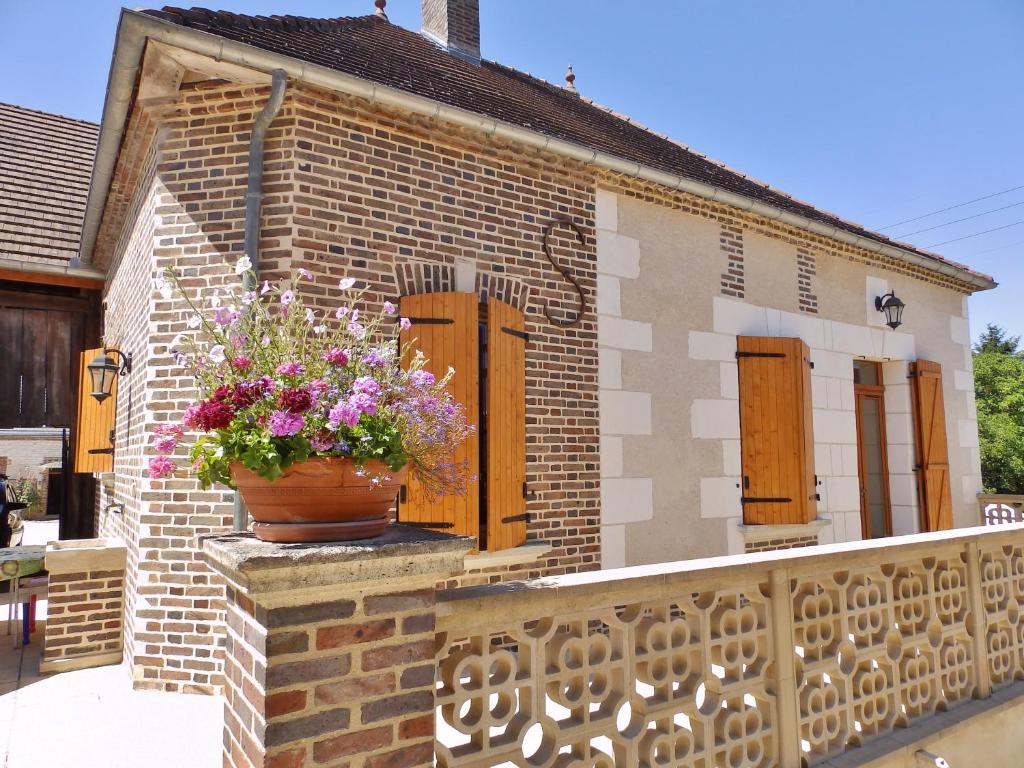 una casa de ladrillo con una maceta de flores en el balcón en GITE LA COLIN'OTHE en Bucey-en-Othe