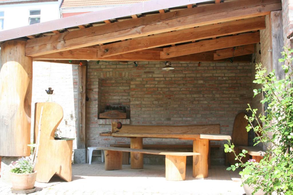 a wooden pavilion with a picnic table in front of a brick wall at Ferienhaus am Wasserturm Angermünde in Angermünde