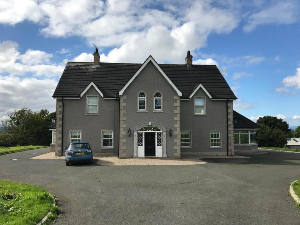 een huis met een auto geparkeerd op een parkeerplaats bij Kilcreeny Lodge in Lisburn