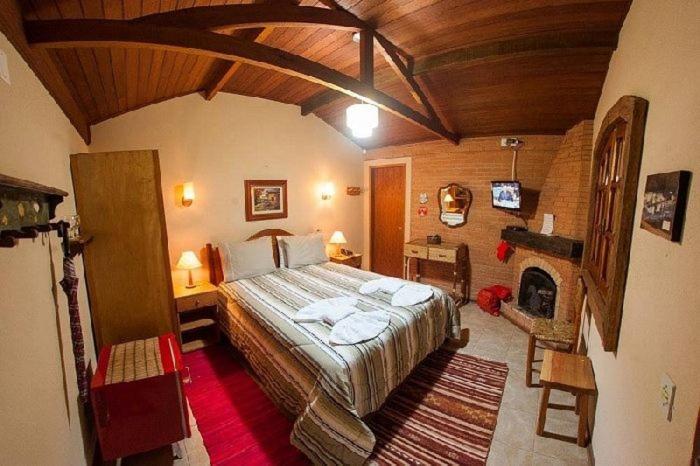 - une chambre avec un grand lit et une cheminée dans l'établissement Pousada Villa do Luar, à Monte Verde