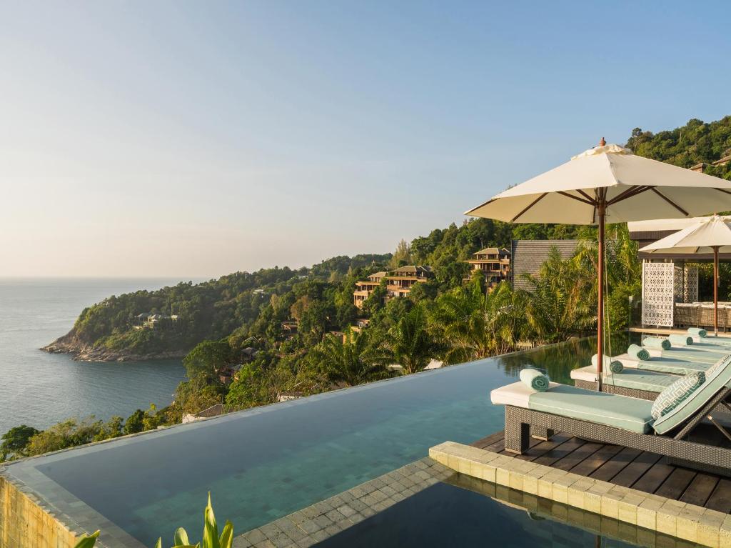 una piscina con sillas y una sombrilla y el océano en Villa Samira by Elite Havens, en Kamala Beach