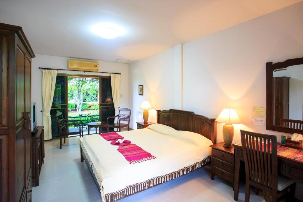 1 dormitorio con cama, escritorio y espejo en Lilawalai Resort, en Nong Nam Daeng